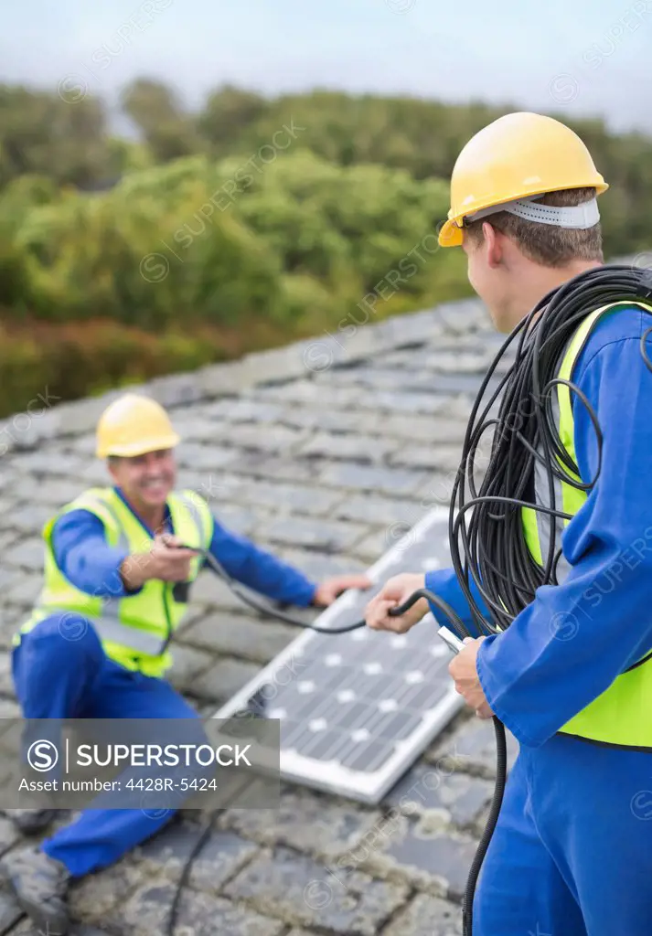 Workers installing solar panel on roof