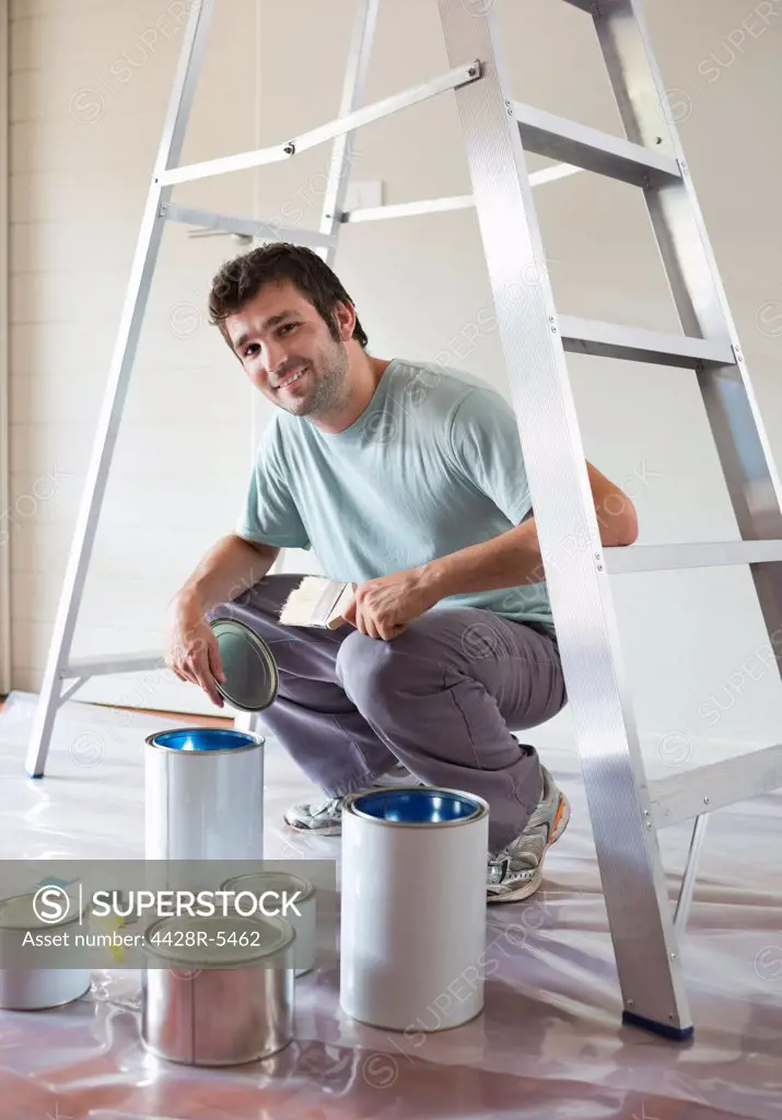 Man examining paint cans in room