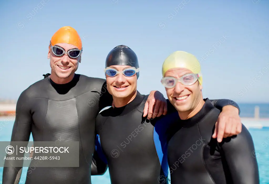 Triathletes in wetsuits smiling together