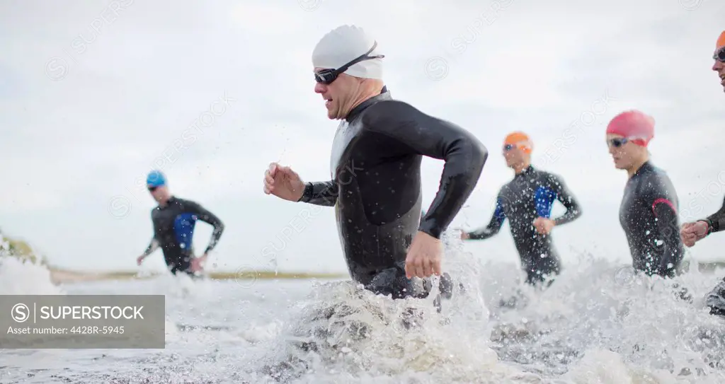 Triathletes in wetsuitsrunning in waves