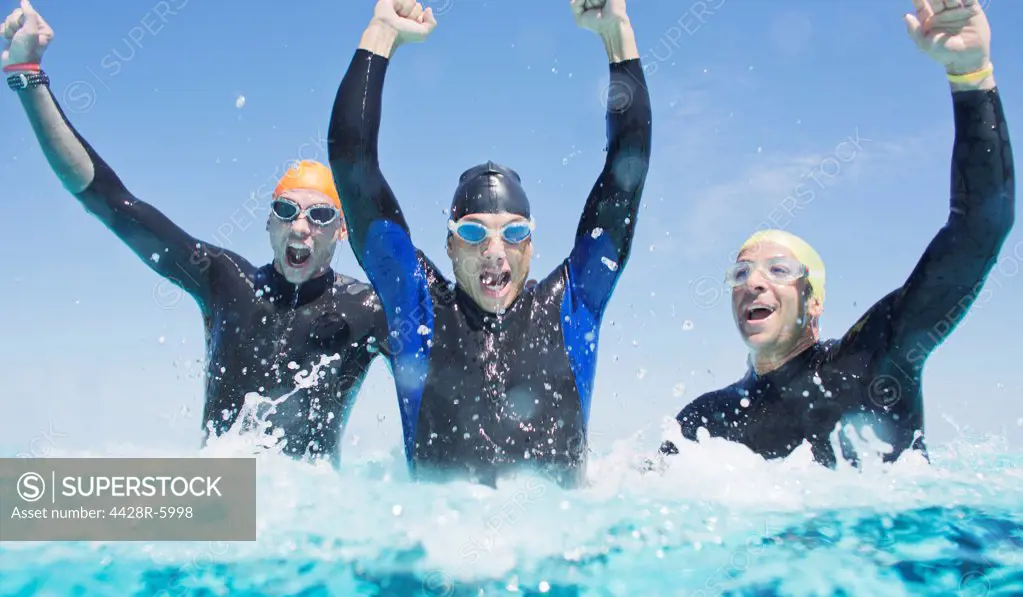Triathletes in wetsuits splashing in waves