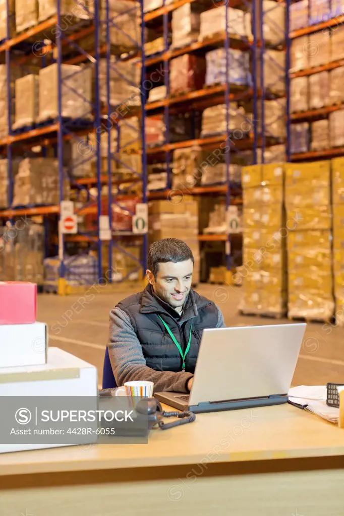 Worker using laptop in warehouse