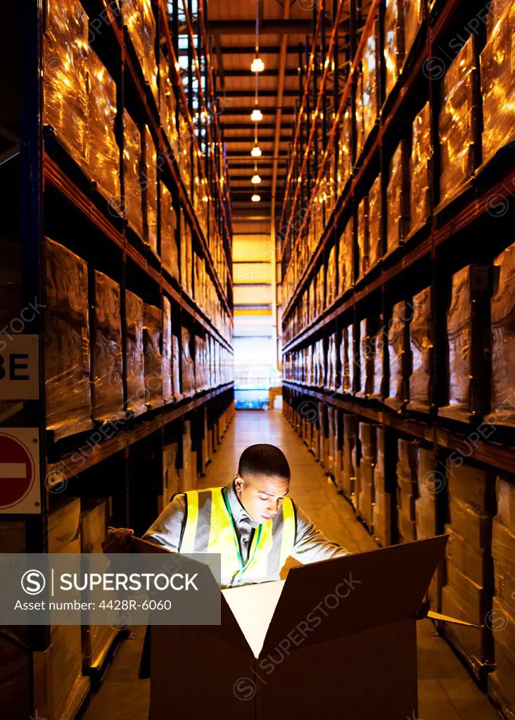 Worker opening glowing box in warehouse
