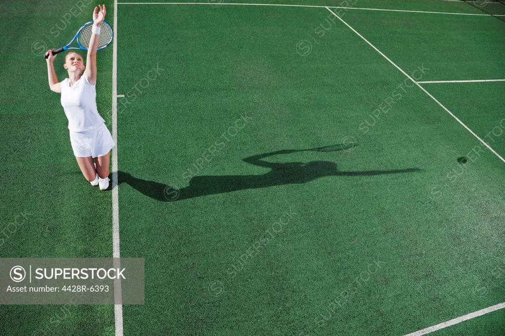 Tennis player serving ball on court