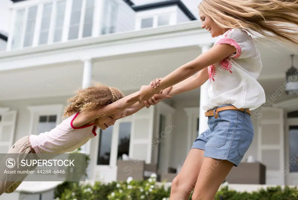 Mother and daughter playing outside house