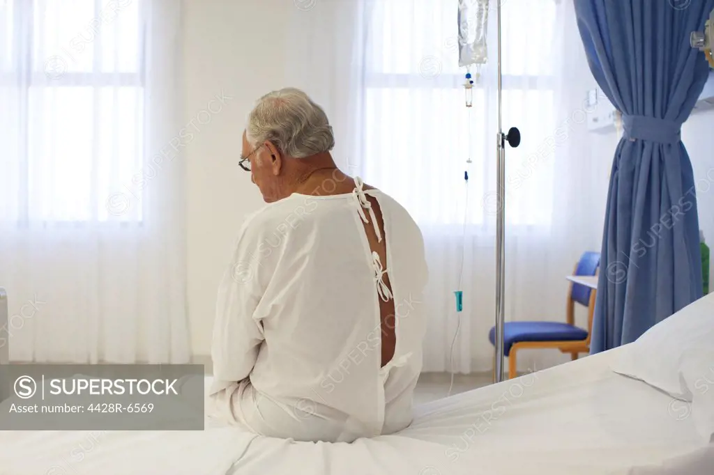 Older patient wearing gown in hospital room