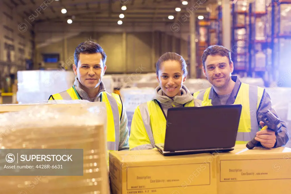 Workers using laptop in warehouse