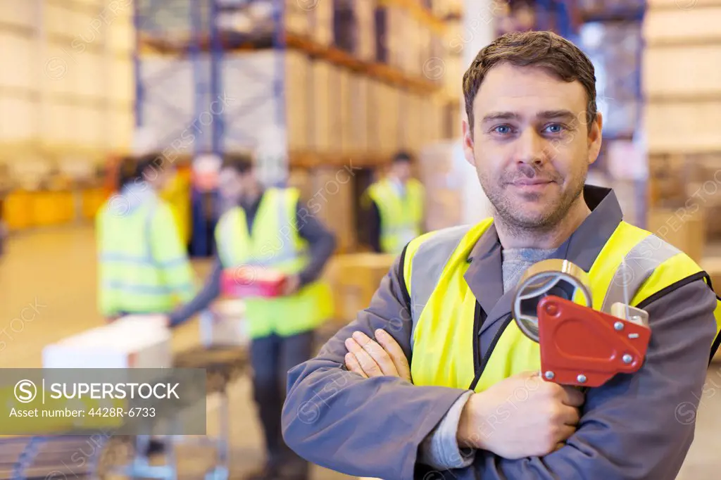 Worker holding tape dispenser in warehouse