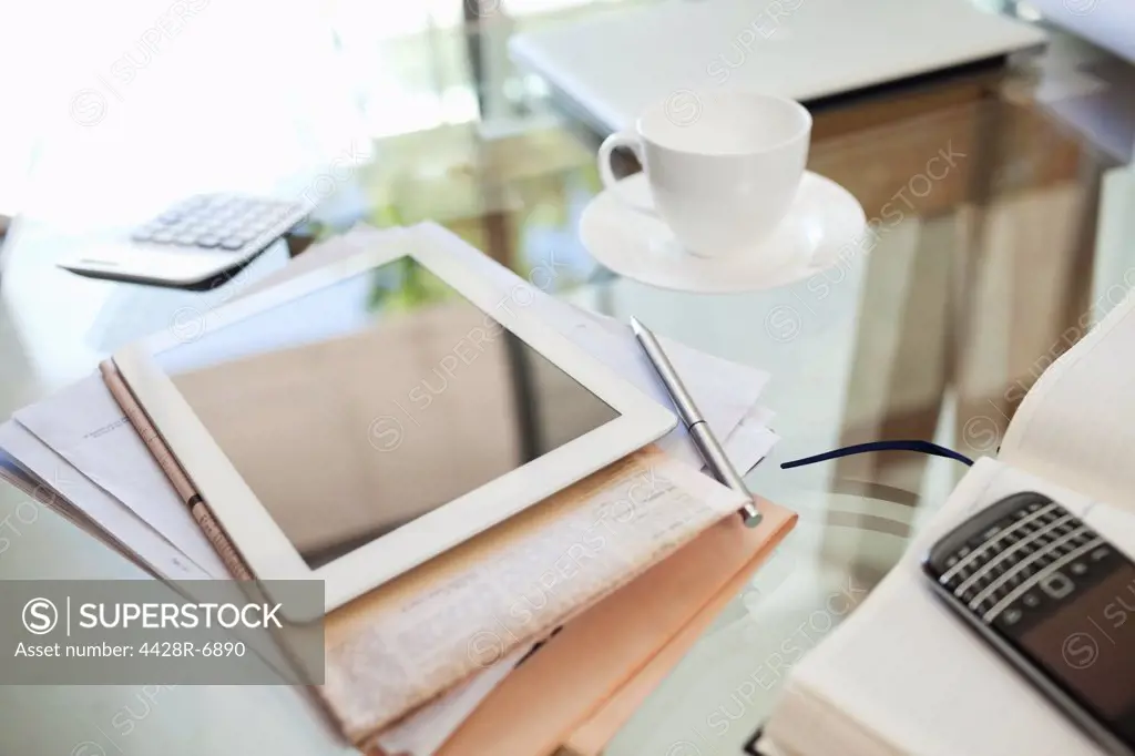 Tablet computer, newspaper, coffee cup and cell phone on desk