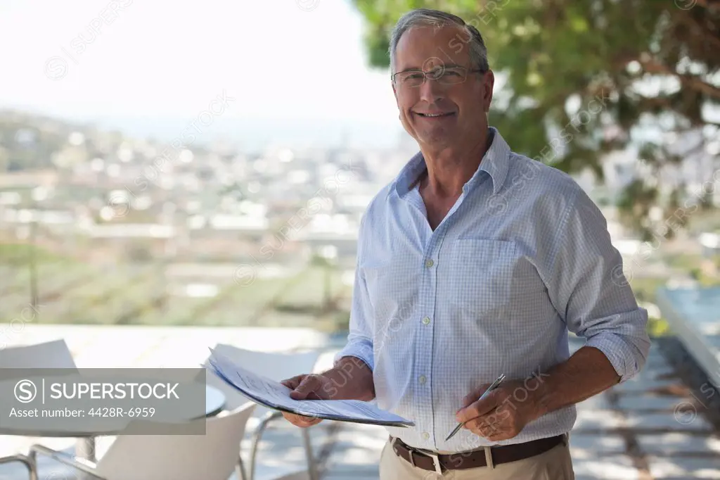 Older man reading papers outdoors