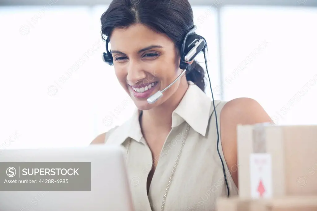 Businesswoman wearing headset at desk