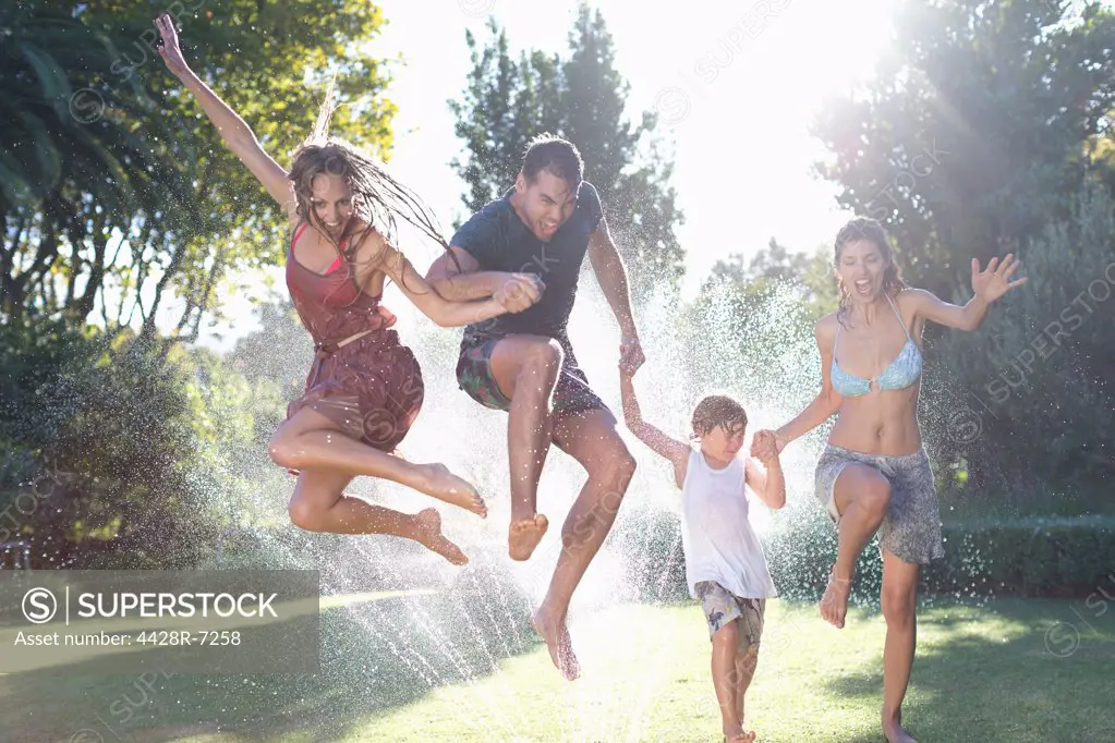 Family jumping in sprinkler