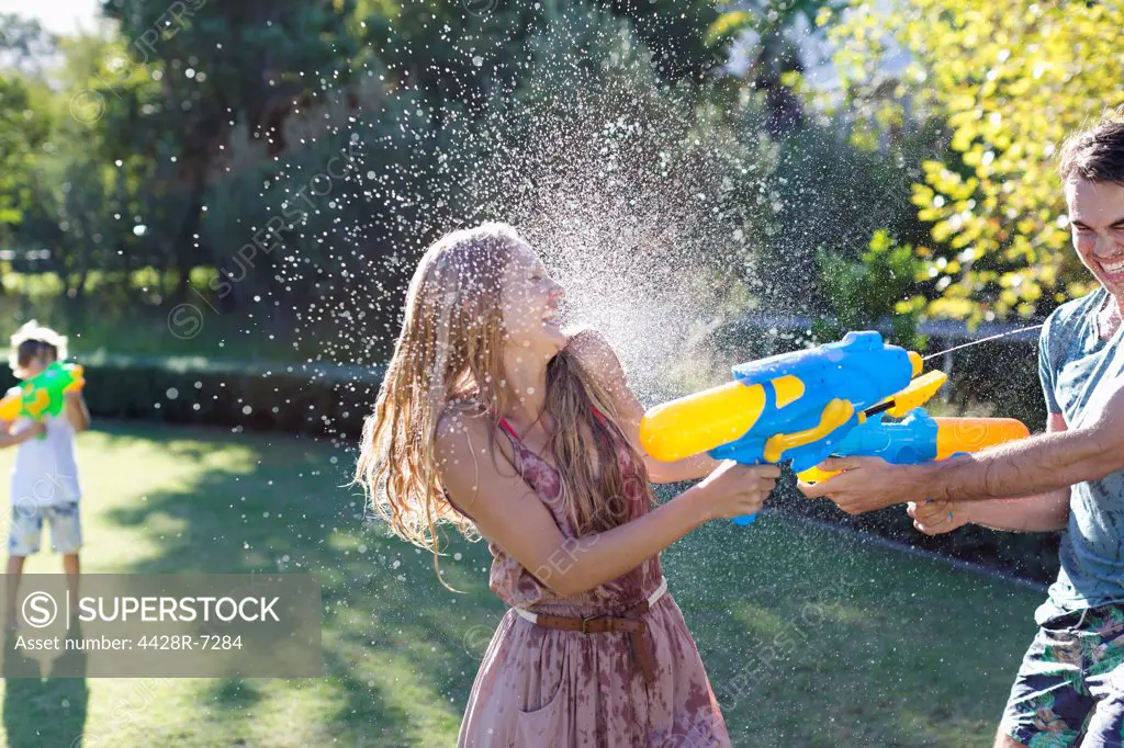 Couple playing with water guns in backyard