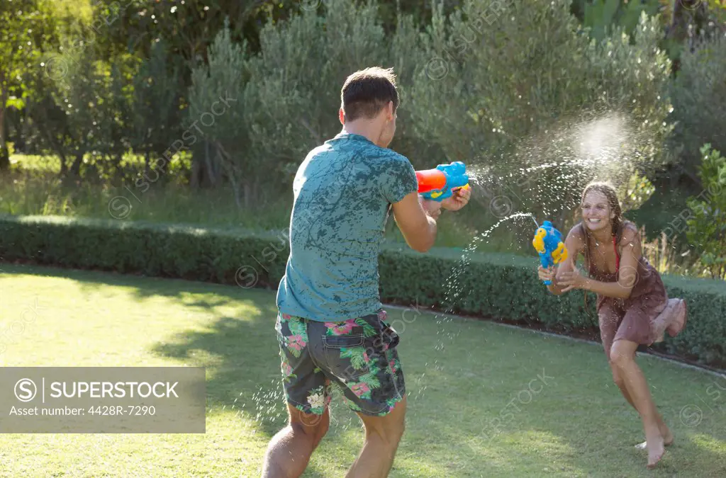 Couple playing with water guns in backyard