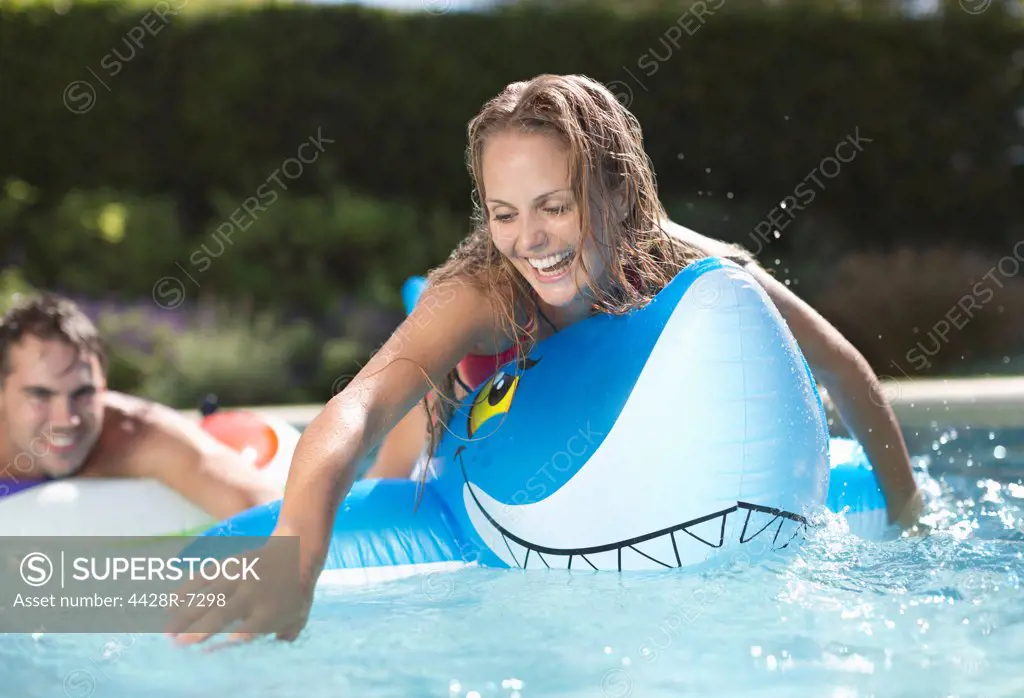 Woman playing on inflatable toy in swimming pool