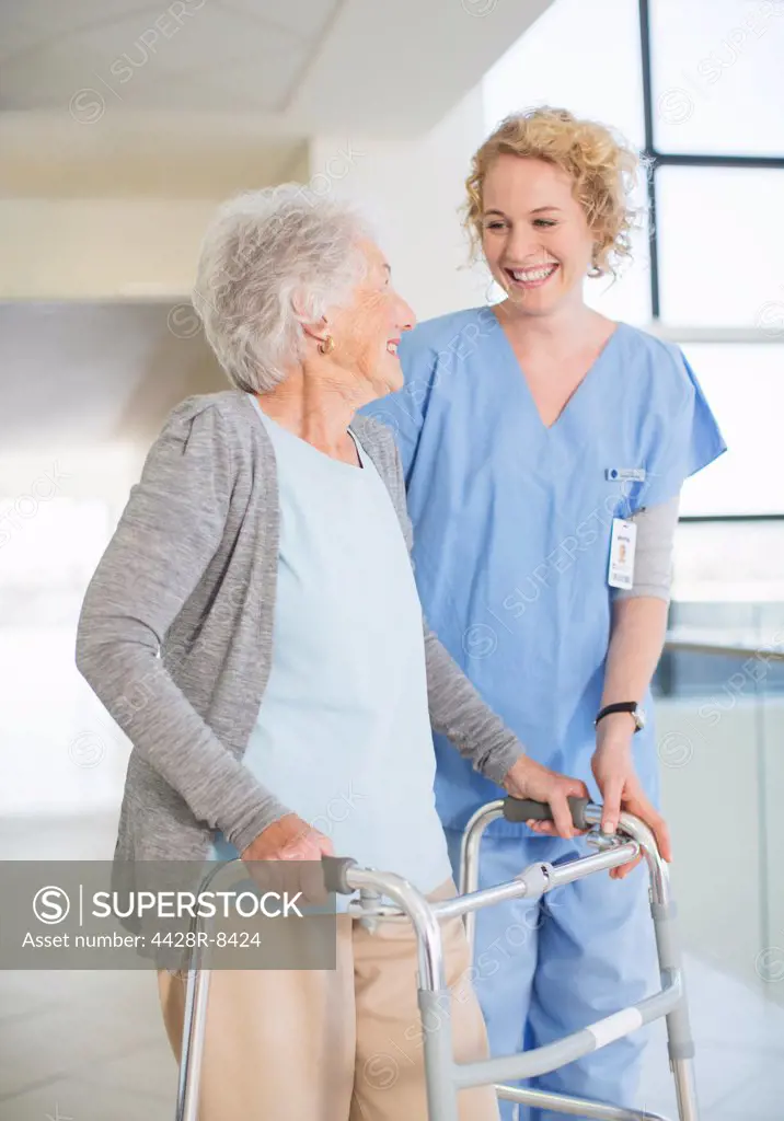 Senior patient with walker smiling at nurse in hospital corridor