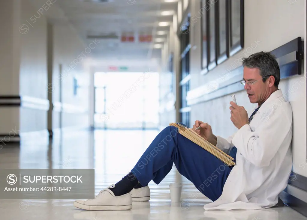 Doctor using dictaphone in hospital corridor