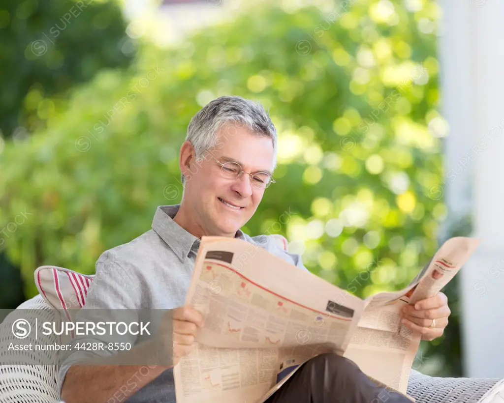 Senior man reading newspaper on patio