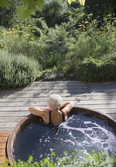 Senior woman relaxing in hot tub on sunny summer patio