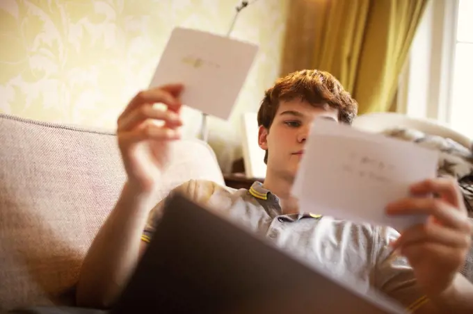 Teenage boy with flash cards studying on sofa