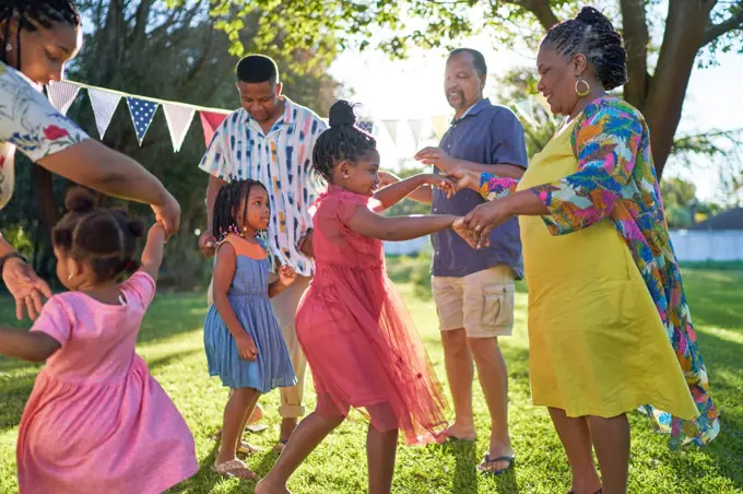 Carefree multigenerational family dancing in summer backyard