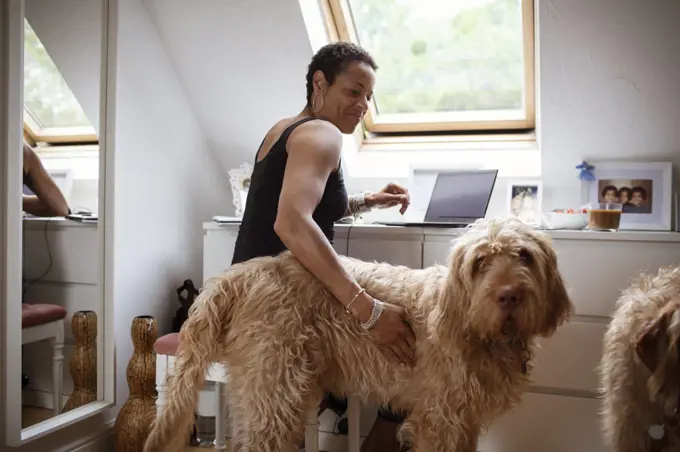 Woman petting Labradoodle dog and working from home