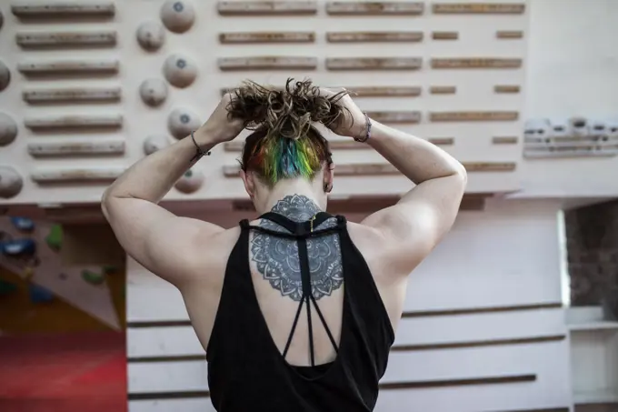 Young woman with mandala back tattoo at rock climbing wall