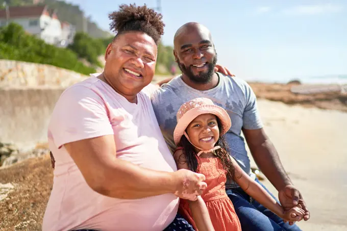 Portrait happy gay male couple with daughter on summer beach
