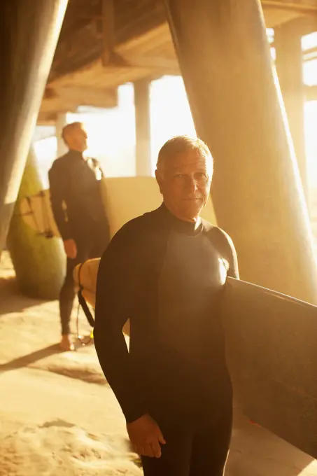 Los Angeles, USA, Older surfers carrying boards under pier