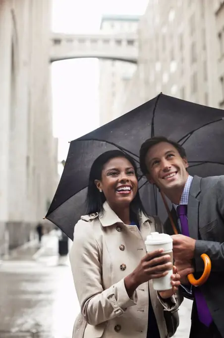 Business people holding umbrella on city street,New York