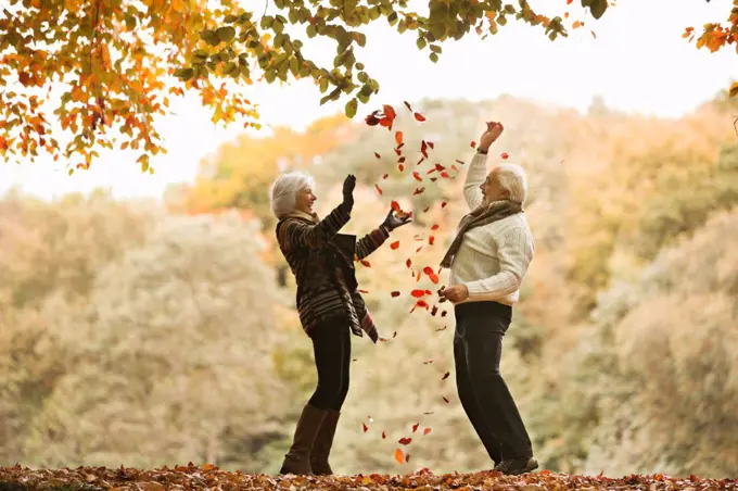 Older couple playing in autumn leaves,London, UK