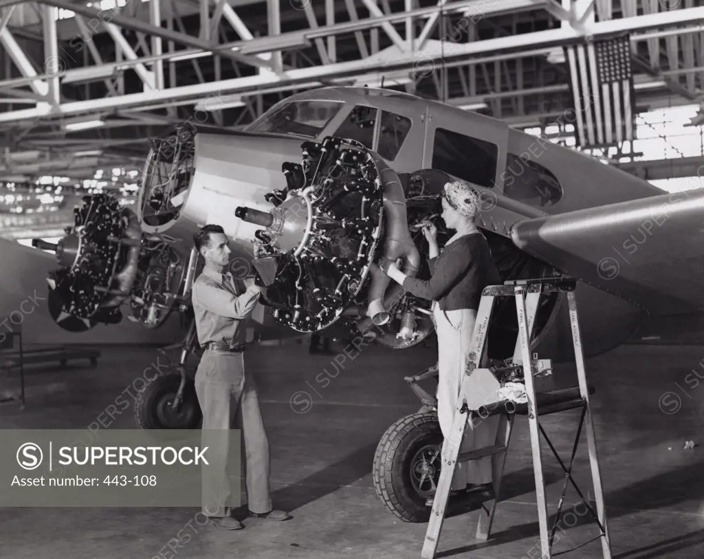 Mid adult man and a mid adult woman examining an airplane, 1943