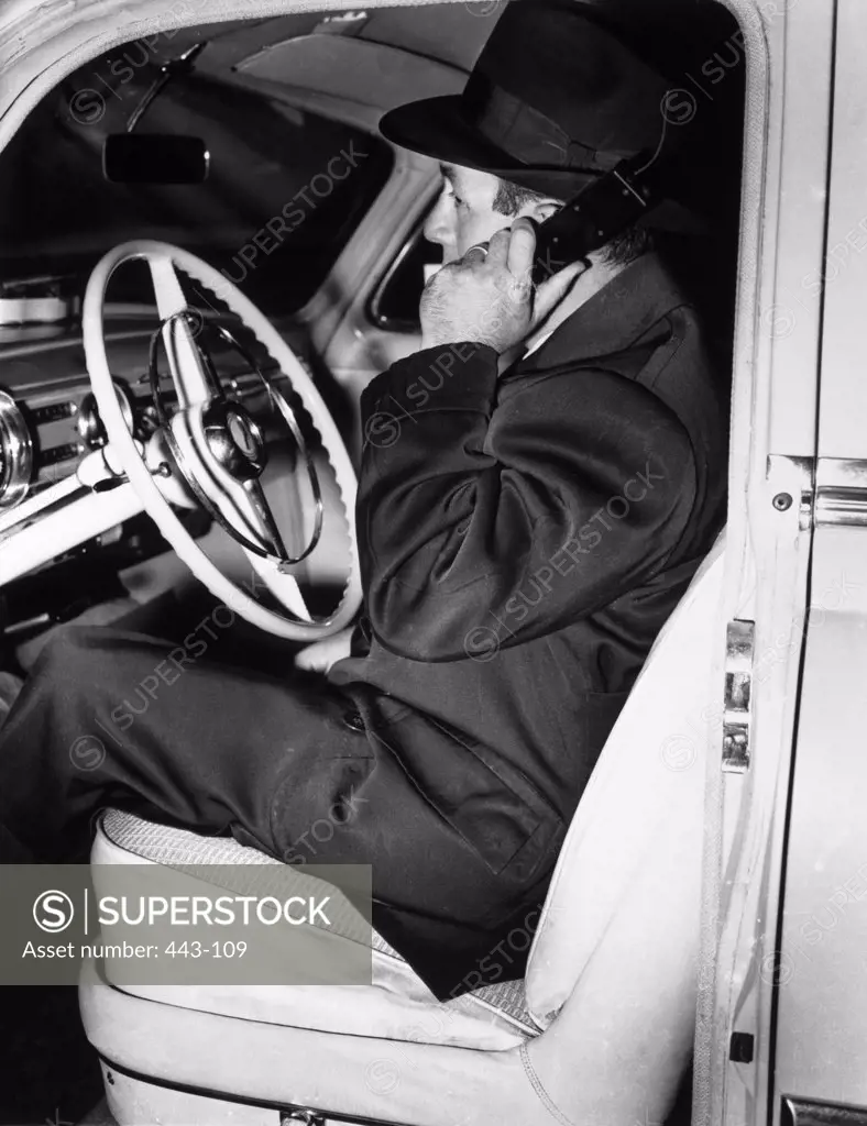 Side profile of a businessman sitting using a car phone, 1954