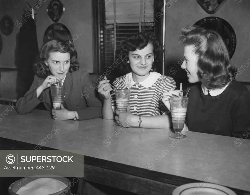 Three young women sitting in a restaurant, 1940
