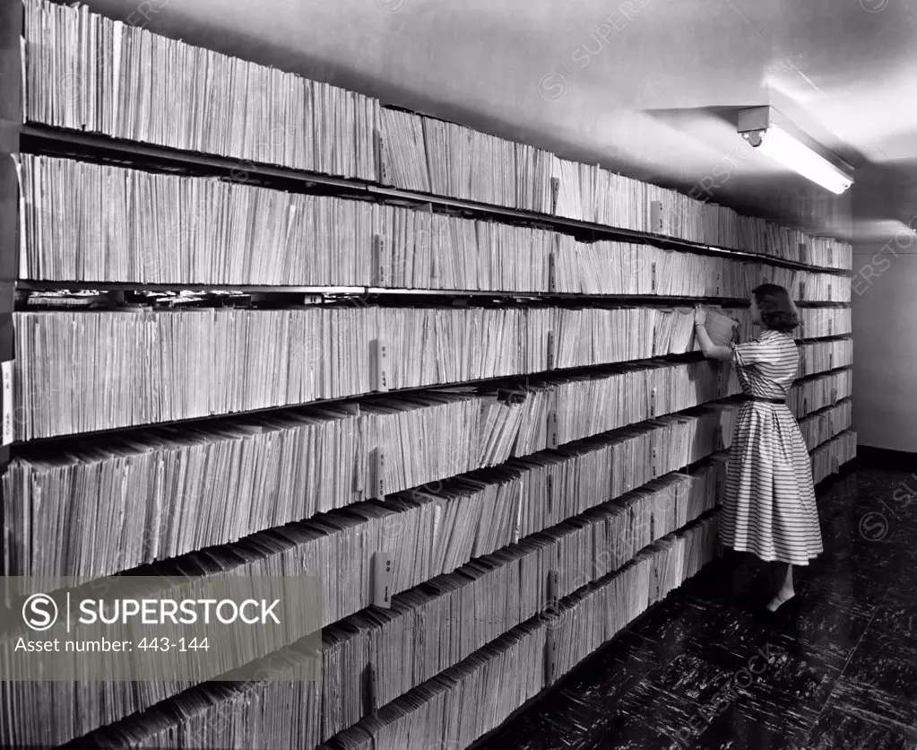 Side profile of a young woman standing in a library, 1952