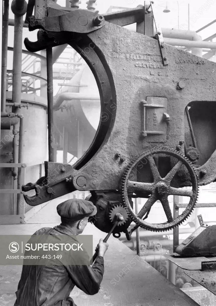 Rear view of a man operating machinery in a factory, 1939