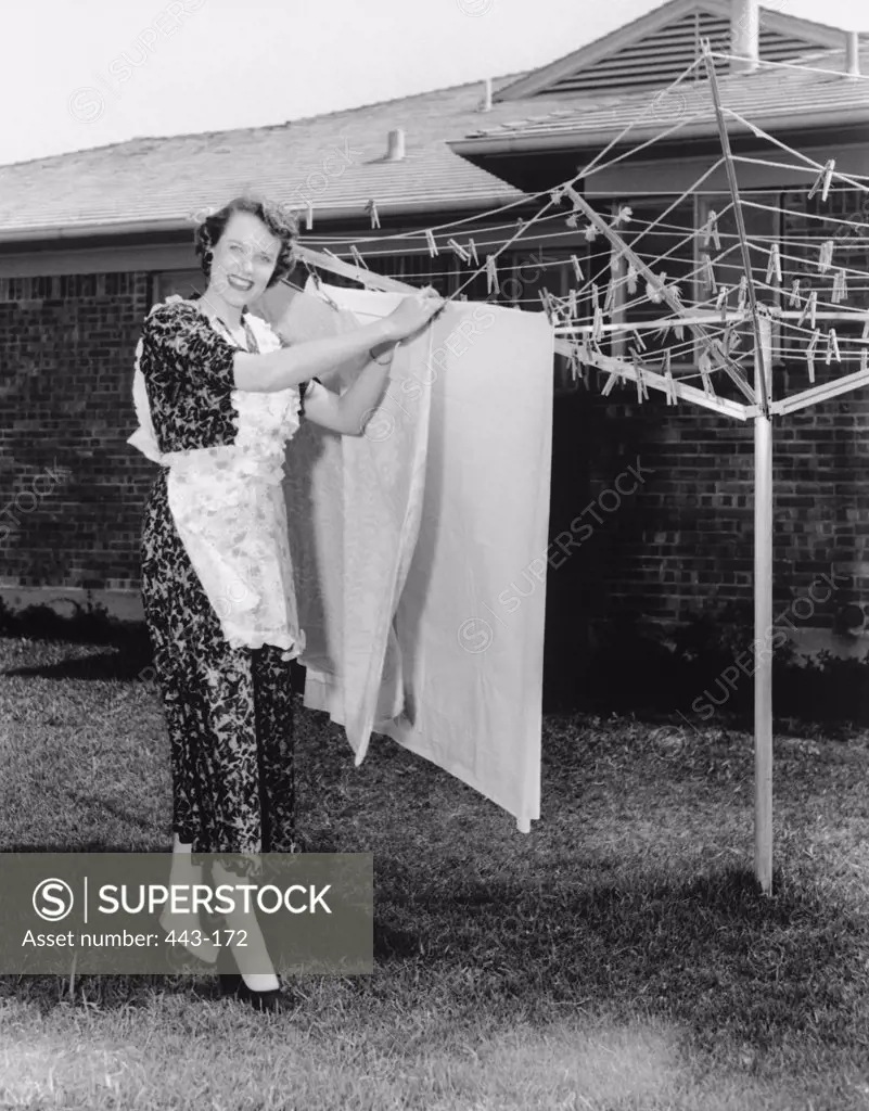 Portrait of a young woman drying clothes on a clothesline, 1950