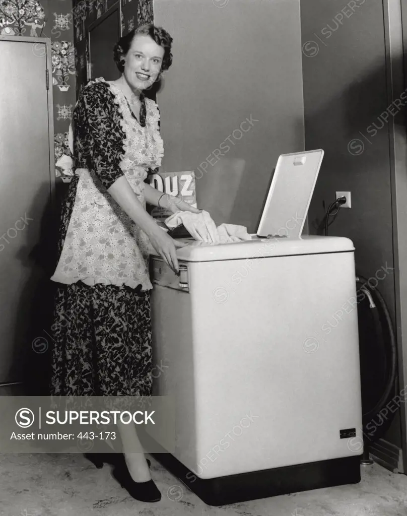 Portrait of a young woman washing clothes in a washing machine, 1950