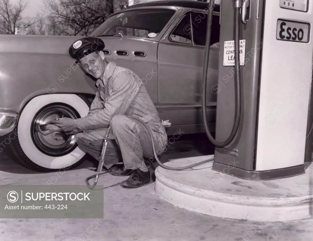 Gas station attendant checking the air pressure in a tire