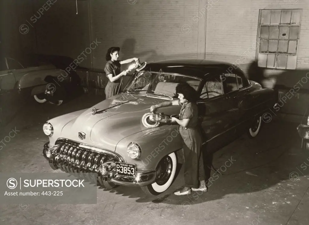 Garage mechanics polishing a car in a garage, 1950