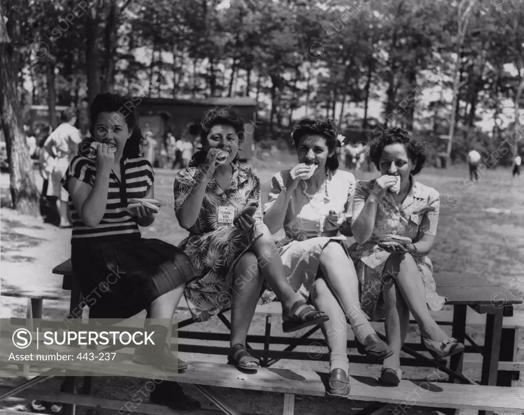 Portrait of four young women eating hot dogs, 1945