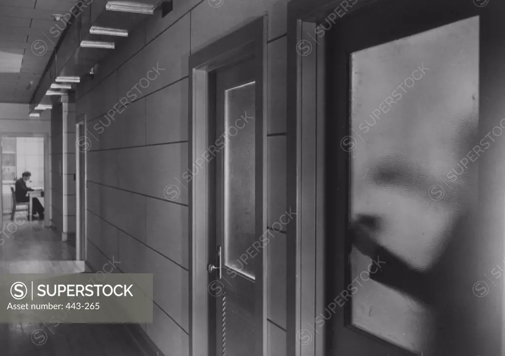 Side profile of a businessman sitting in an office at the end of a corridor