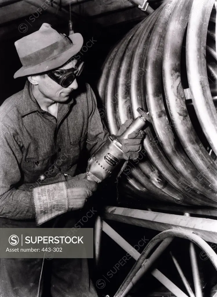 Manual worker using a metal sander in a factory