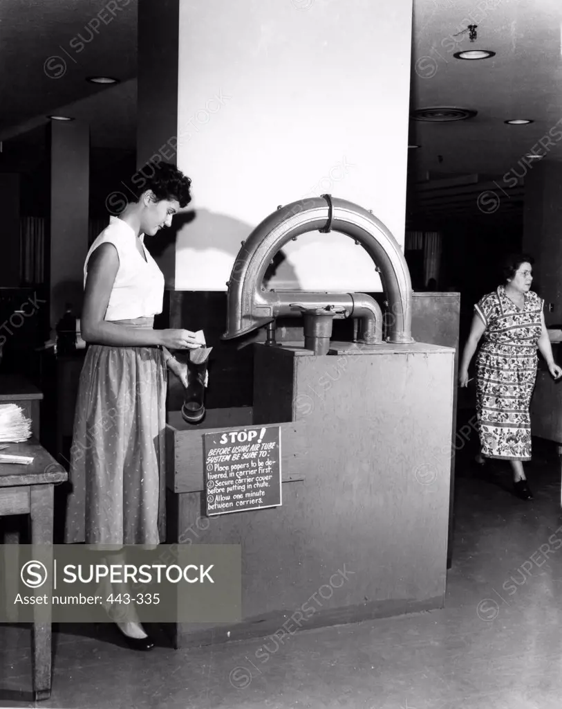 Side profile of a young woman working on a pneumatic tube message system