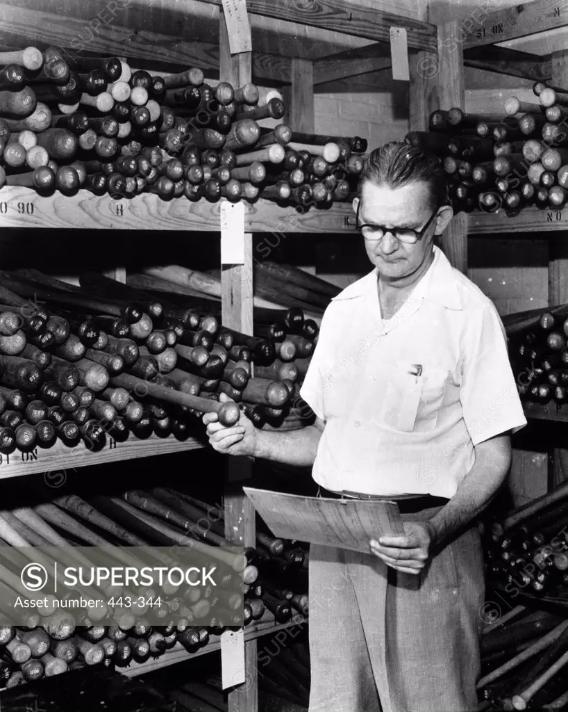 Senior man inspecting a baseball bat in a warehouse