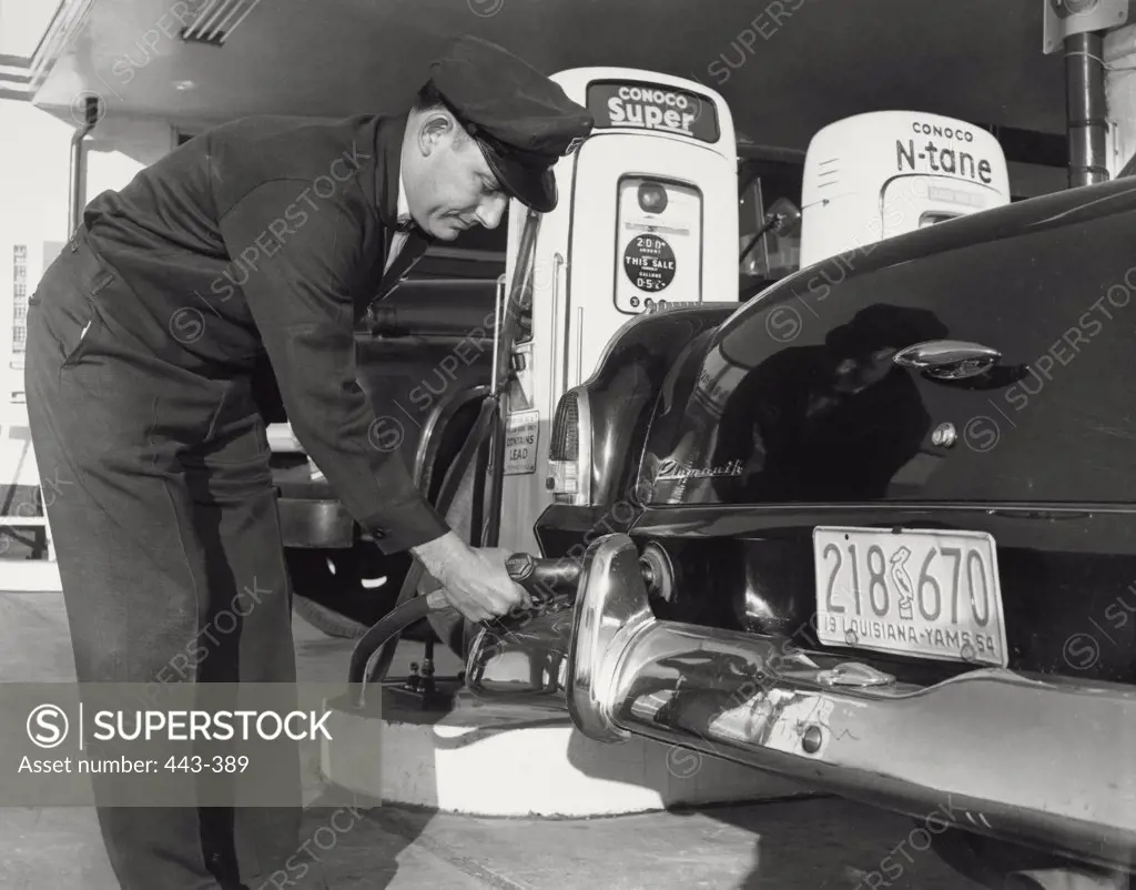 Gas station attendant putting gas in a car, 1954