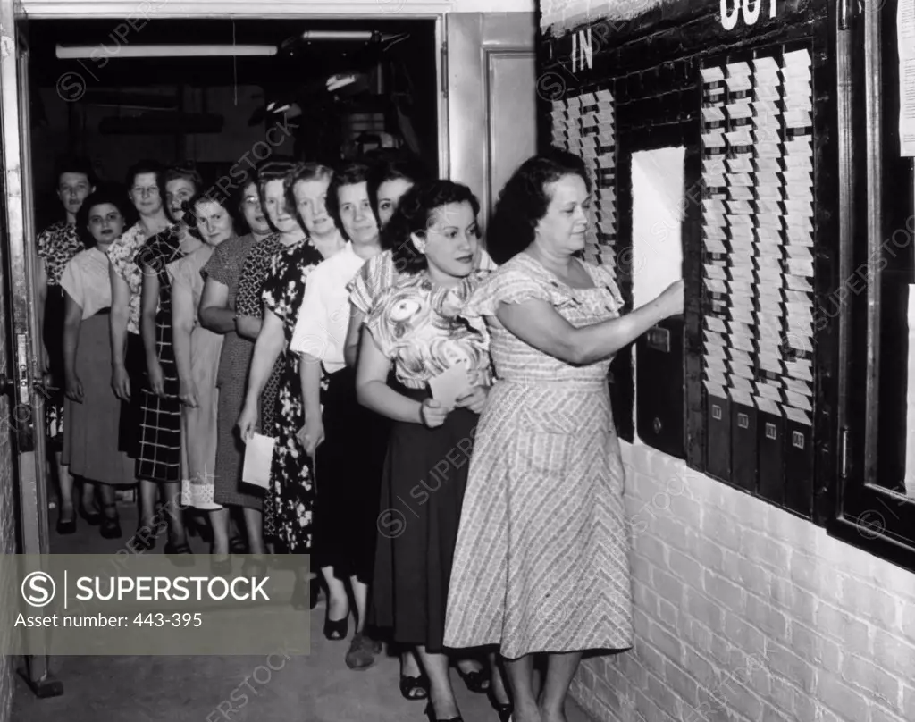 Group of female office workers standing in line to punch time cards