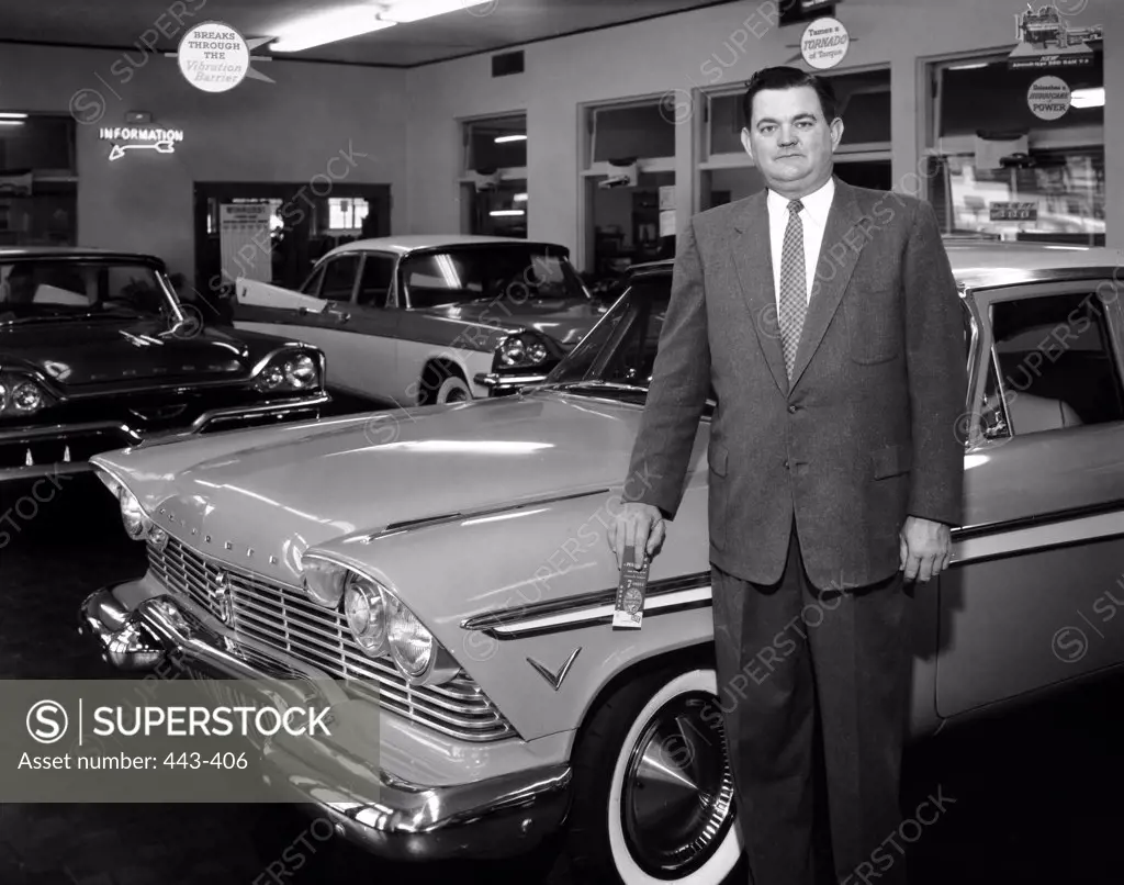 Portrait of a mature man standing near a car in a showroom