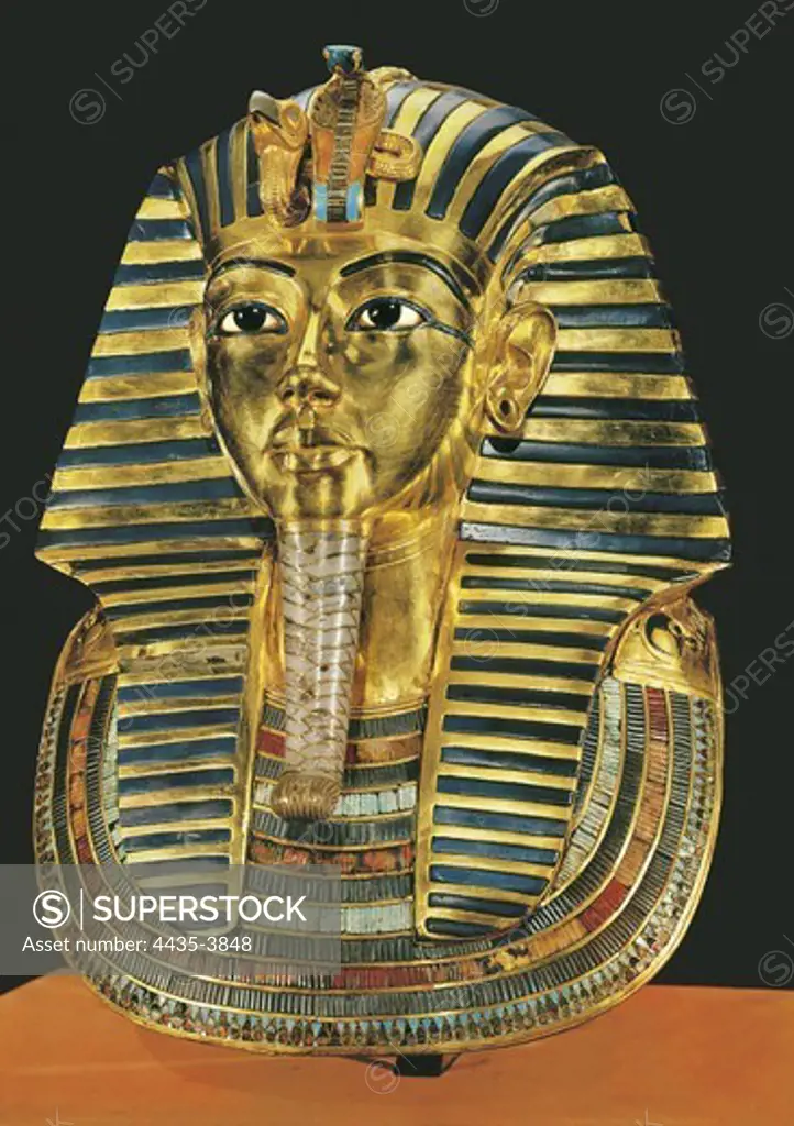 The gold mask. ca. 1340 BC. Gold Mask made in wood, gold, coloured vitreous paste and hard stones inlays. Situated at the third in mummiform coffin of the Treasure of Tutankhamun. Egyptian art. New Kingdom. Jewelry. EGYPT. CAIRO. Cairo. Egyptian Museum. Proc: EGYPT. QUENA. Dayr al-Bahri. Valley of the Kings. Tomb of Tutankhamun.