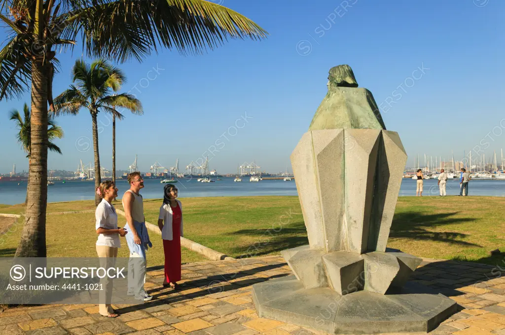 Tourists looking at statue of Bartholomew Diaz on the Victoria Embankment with the harbour in the background. Durban. KwaZulu Natal. South Africa.